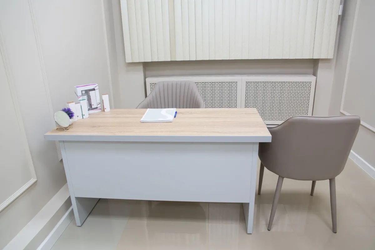 Mesa de atendimento com duas cadeiras num consultório claro