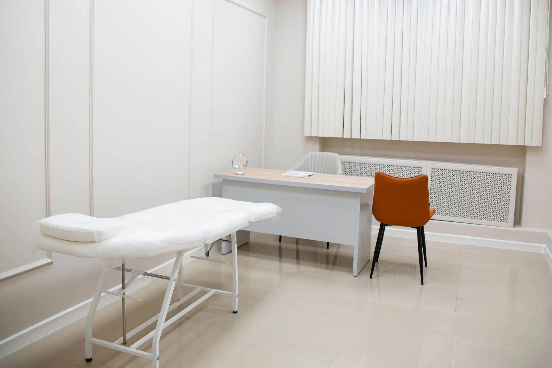 Consultório com mesa, cadeiras e maca de exame